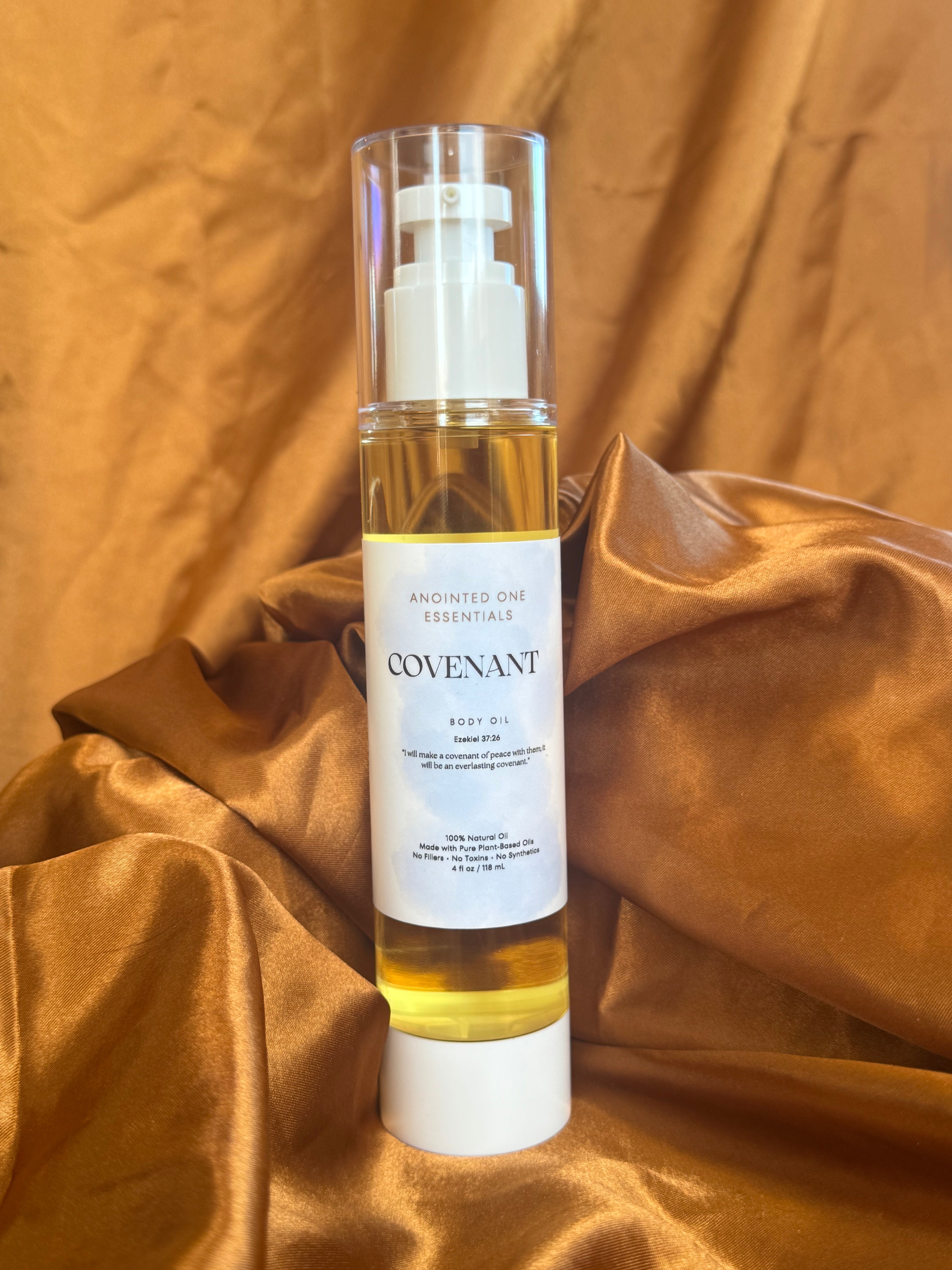 Bottle of Covenant body oil on a gold fabric background