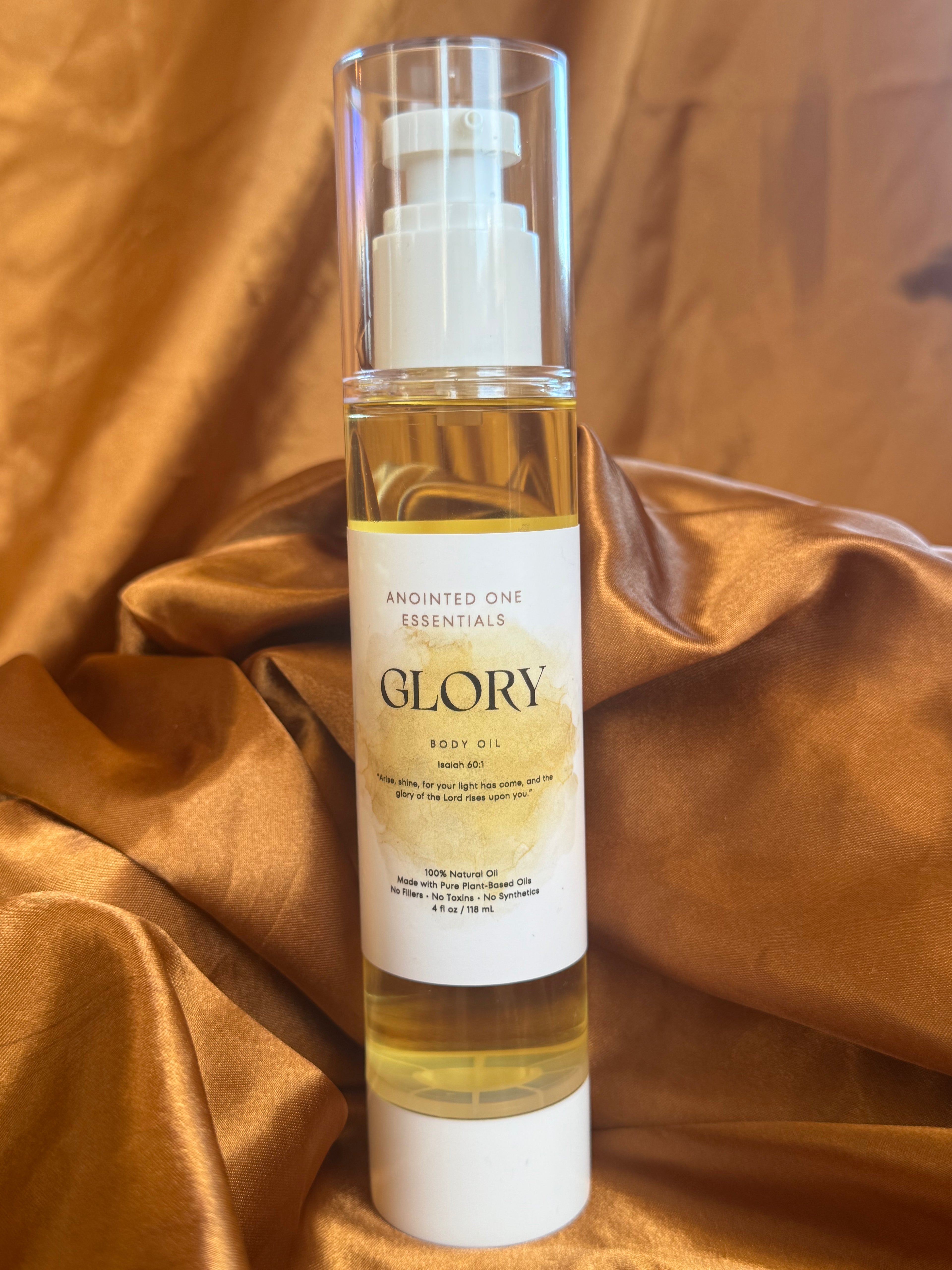 Bottle of 'Glory' body oil on a textured brown fabric background